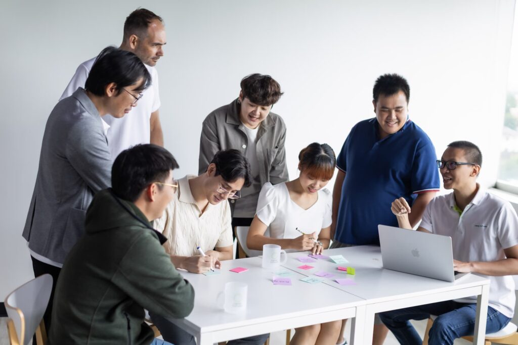Collaborative team of diverse professionals brainstorming ideas with sticky notes and laptop during an office workshop meeting