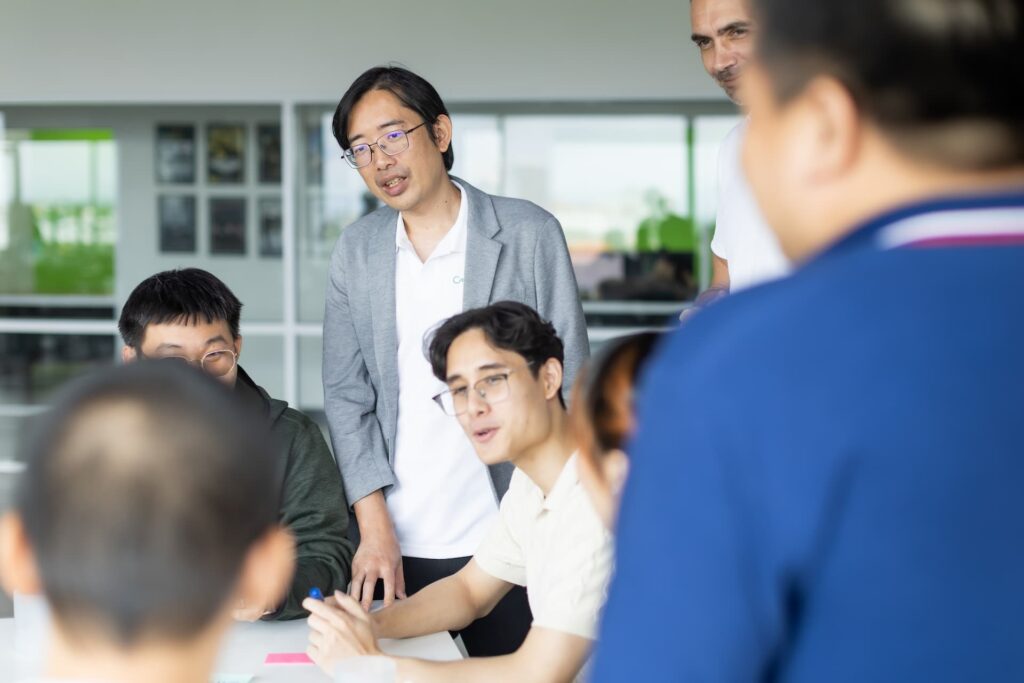 Team leader in blazer presenting and discussing ideas with colleagues around a table in a bright modern office workspace