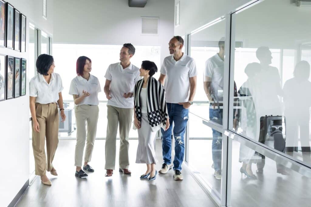 Group of business professionals discussing software development in an office hallway.